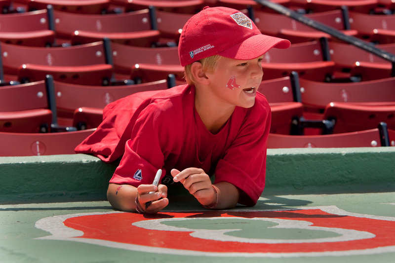Dillon Bolduc of South Portland makes some memories by signing the top of the Sea Dogs dugout.