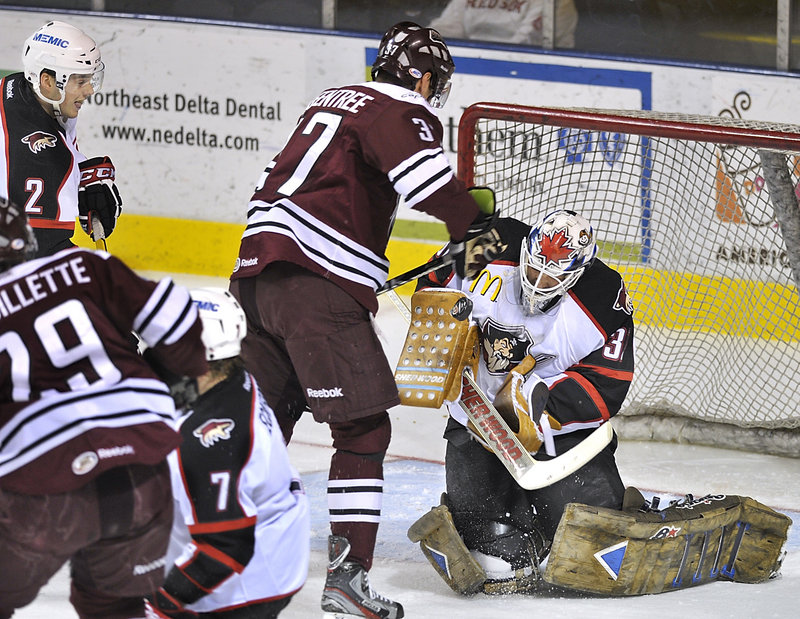 Portland goalie Peter Mannino makes a tough save, then keeps control of the puck in front of Kyle Greentree of the Hershey Bears in the first period Friday night. Portland won 6-4 and will end its regular season Sunday at the Providence Bruins.