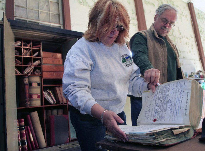 Anne Clark, town clerk and tax collector in Milton, N.H., and Town Administrator Tony Mincu look through old ledgers discovered in a long-locked town safe in the old town hall Saturday. It took a locksmith three hours to open the safe.