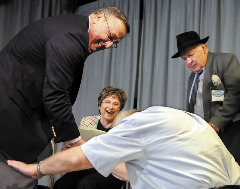 Pat Thatcher’s comical greeting of Gov. Paul LePage, left, elicits laughter from LePage, tax activist Mary Adams and John Frary at a Tax Day Rally in Lewiston on Sunday.