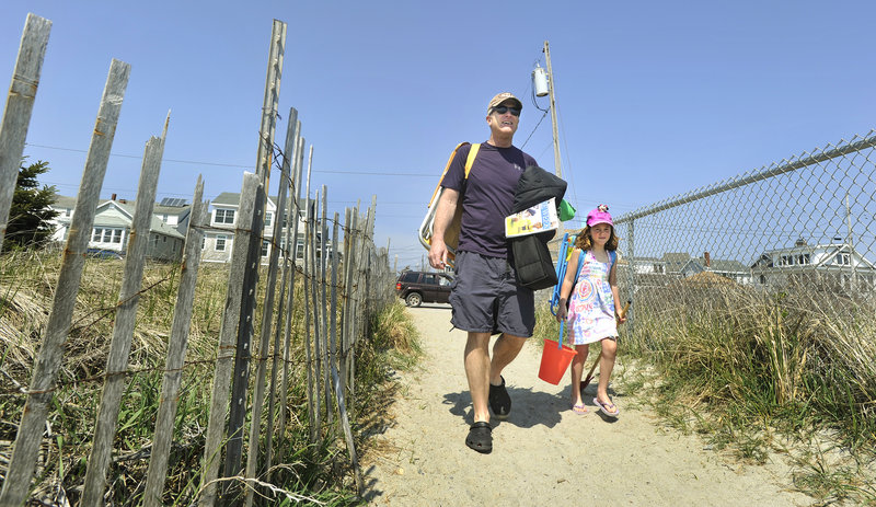 Bill Dwyer of Portland and his daughter Ruby, 5, head for some fun in the sun Monday at Higgins Beach. Dwyer, a frequent beach visitor, said that if the parking fee at Higgins doubled to $10, he would consider paying $65 for a townwide beach parking pass for non-residents.