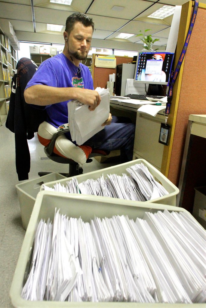 Illinois Department of Revenue office associate Jeff Mumaw processes 2011 income tax forms Monday.
