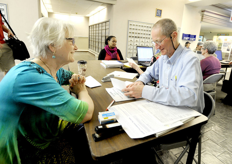 R.J. Harper, right, an IRS-certified volunteer tax preparer, assists last-minute filer Ana Dana from South Portland at a desk set up Tuesday afternoon in the lobby of the Forest Avenue post office.