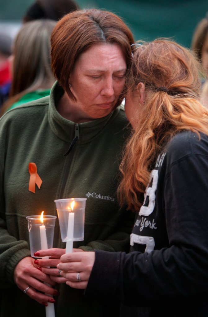 Valerie Page, wife of Sean Page, is comforted by a friend during a candlelight memorial at her home in Biddeford on Wednesday night. About 100 people attended the event.