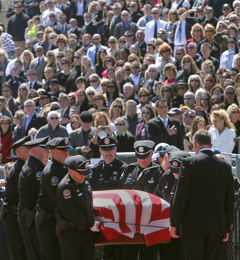 Thousands of mourners watch as officers from the Greenland (N.H.) Police Department carry the body of their chief, Michael Maloney, during his funeral service in Hampton, N.H., on Thursday. Maloney, 48, was fatally shot in a drug raid last week; four other officers who were wounded in the raid were in attendance at the ceremony.