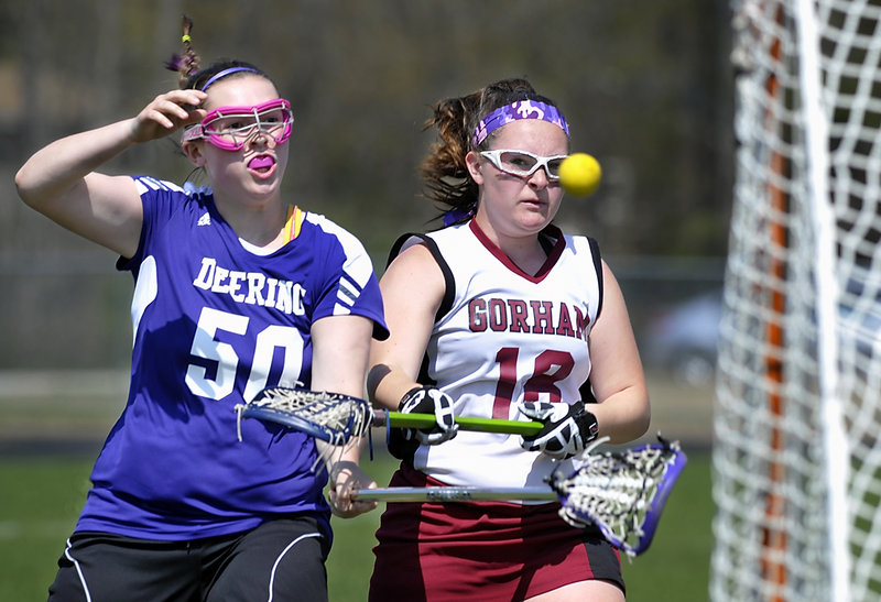 Ashley Gaudette, who scored six goals Friday for Gorham in an 18-8 victory against Deering, fires in a shot while tightly defended by freshman Maddy Reid of Deering in a girls’ lacrosse opener.