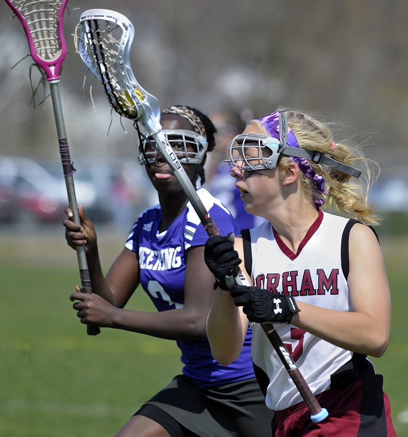 Emily Lewis of Gorham takes the ball downfield while Nyalat Bilieu of Deering keeps a close watch. Lewis had a goal during Gorham’s 18-8 season-opening victory.
