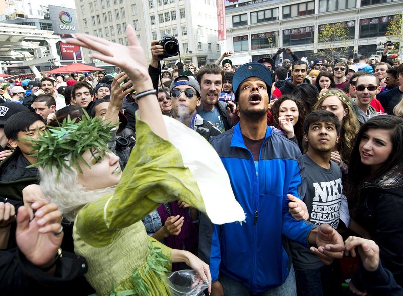 The “Weed Fairy,” whose name was not available, throws marijuana joints to the crowd as thousands take part in the annual marijuana 4/20 smoke-off at Dundas Square in Toronto on Friday.