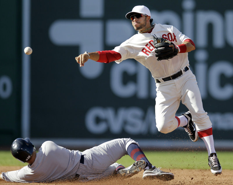 Mike Aviles of the Red Sox turns a double play over New York’s Nick Swisher. Both teams wore throwback uniforms with no numbers on Fenway Park’s 100th anniversary.