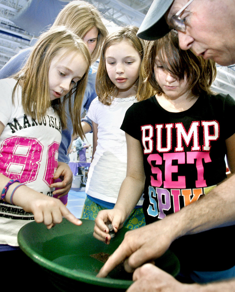 Bill White of Coos Canyon Rock points out flakes of gold to first-time panners Maggi Bradford, 10; Annika Thaler, 16, an exchange student living with the Bradfords; Sophie Sangster, 11, and Savana Bradford, 8, all of Raymond, at the 29th annual Gem and Mineral Show.