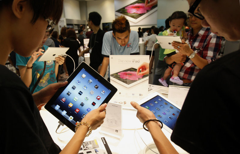 Shoppers look at new iPad tablet computers at an Apple store in Klang, Malaysia. Apple is set to report another record quarterly profit today.