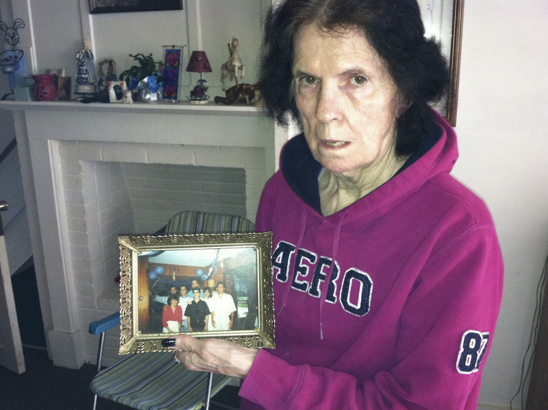 “I’m coping as best I can,” said Carol Swenson, the mother of slaying suspect Michael Swenson. She holds a family photo in her Scarborough home Wednesday. “I’m very upset and hope it wasn’t true,” she said after her son’s arrest.