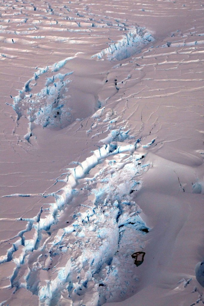 A deep crevasse forms in an ice shelf as an iceberg, left, breaks off. Research using an ice-gazing satellite, shows ice shelves are melting from warm water below, not just from warmer air. Wind current changes are pushing warmer water closer to and beneath the floating ice shelves.