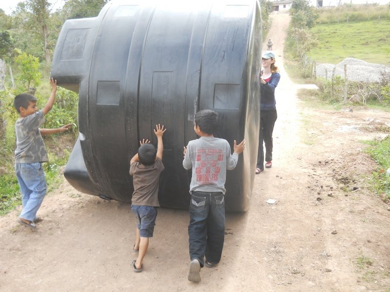 Honduran youths roll one of five septic tanks for a massive wastewater system designed and built by the UMaine chapter of Engineers Without Borders.