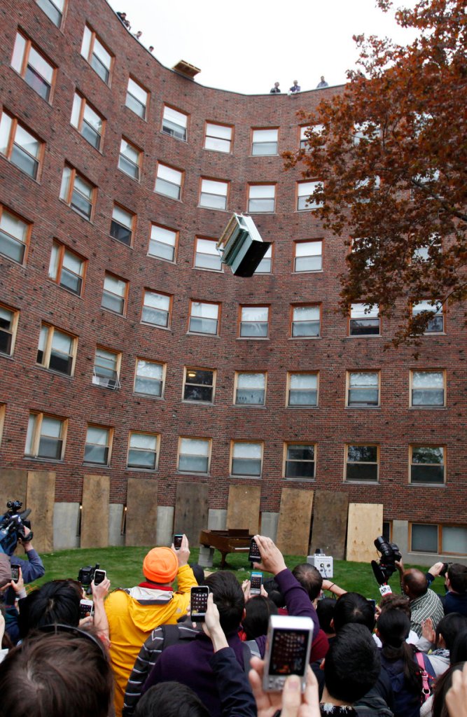 A crowd watches as an upright piano falls from the roof of the Baker House dormitory onto a second piano, a baby grand, at the Massachusetts Institute of Technology in Cambridge, Mass., on Thursday.