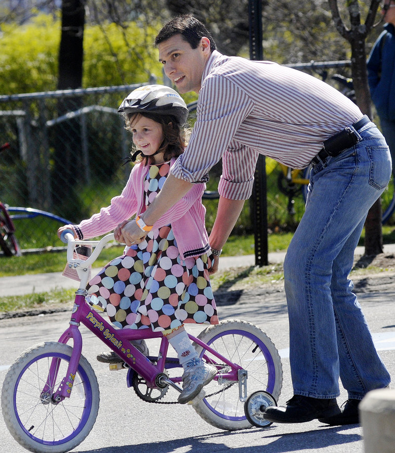 Sam Zager of Portland helps his daughter Maya, 5, as she tries out a bike. Members of the Bicycle Coalition of Maine were on hand at the swap to answer questions and offer advice.