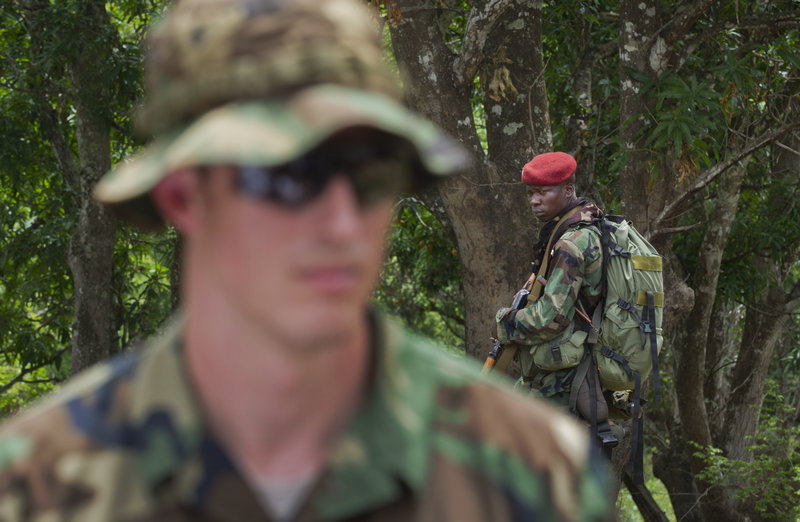 A soldier from the Central African Republic, right, looks across as U.S. Army special forces Capt. Gregory, 29, left, who would give only his first name in accordance with security guidelines, speaks Sunday with other troops from the Central African Republic and Uganda, where they’re searching for warlord Joseph Kony, in Obo, Central African Republic.