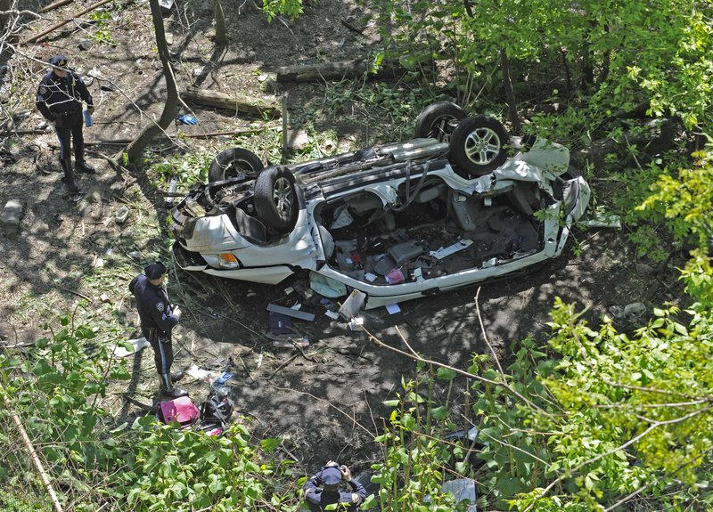 Police examine the wreckage of a van that plunged off the Bronx River Parkway and into a ravine on Bronx Zoo property Sunday in New York. It’s the second time in a year that a vehicle has fallen off the same stretch of the parkway.