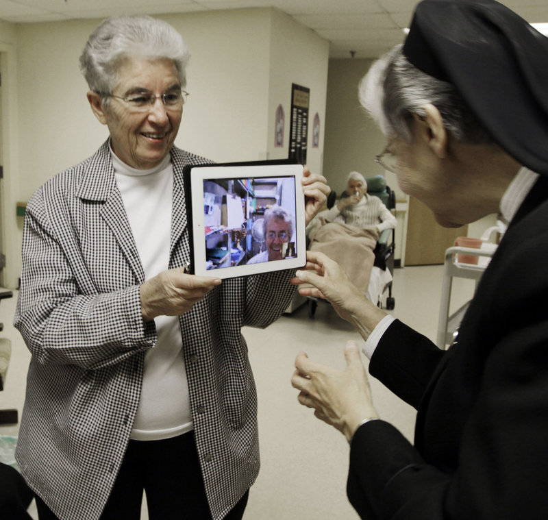 Priscille Roy, left, shows Sister Elaine Lachance an iPad with the image of a colleague who is in Brazil, Sister Pauline Demers, at St. Joseph Convent in Biddeford.