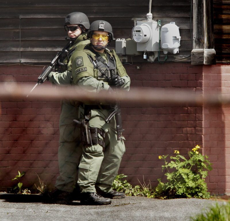 Heavily armed members of Portland Police’s Special Reaction Team position themselves on Cedar Street while trying to apprehend shooting suspect Brian Kelley in Portland on Saturday.