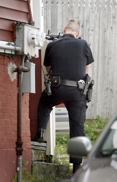 Portland Police Officer Kevin Haley on Oxford Street aims a gun at the back of 19 Cedar St.