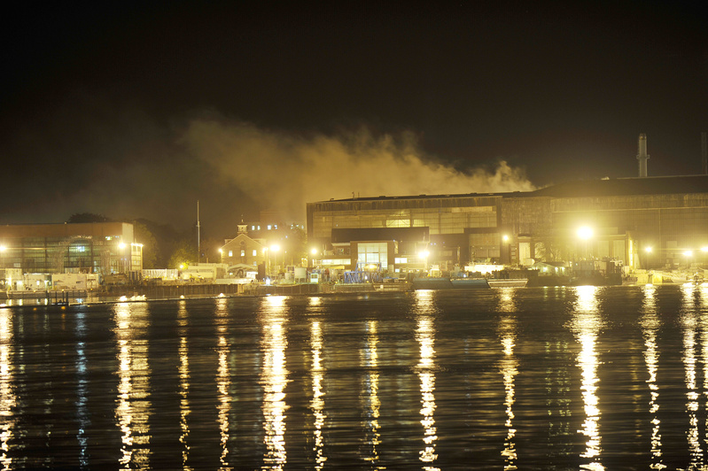Smoke continues to rise from the fire aboard the USS Miami submarine, docked at the Portsmouth Naval Shipyard in Kittery, seen here from across the Piscataqua River in Portsmouth, N.H.