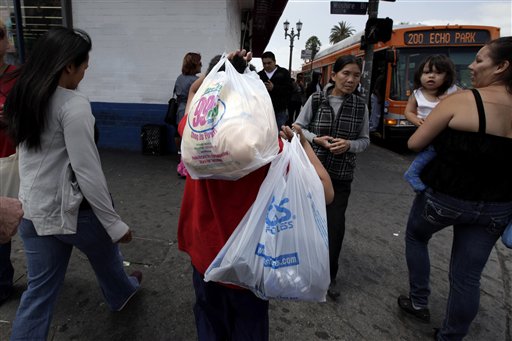 A boy carries plastic bags as he crosses a street in Los Angeles, Thursday, May 24, 2012. Now that the city of Los Angeles has taken the first step toward banning plastic bags, it appears the little utilitarian bags themselves may be headed for the trash heap of history. (AP Photo/Jae C. Hong)