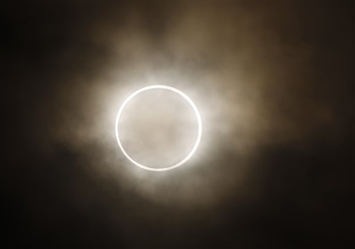 The moon slides across the sun, showing a blazing halo of light, during an annular eclipse at a waterfront park in Yokohama, near Tokyo, Monday, May 21, 2012. Millions of Asians watched as a rare "ring of fire" eclipse crossed their skies early Monday. The annular eclipse, in which the moon passes in front of the sun leaving only a golden ring around its edges, was visible to wide areas across the continent. (AP Photo/Shuji Kajiyama)