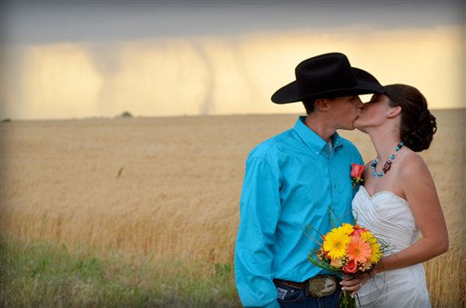 In this May 19, 2012, photo provided by Cate Eighmey, Caleb & Candra Pence pose for a wedding photo as a tornado swirls in the background after they were married in Harper County, Kan. (AP Photo/Cate Eighmey) MANDATORY CREDIT