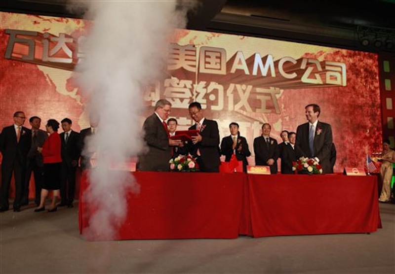 Gerry Lopez, CEO of AMC Entertainment Holdings, center left, exchanges documents with Zhang Lin, vice president of Wanda during a signing ceremony for Dalian Wanda Group Co. to acquire AMC Entertainment Holdings in Beijing, China, Monday, May 21, 2012. The Chinese conglomerate announced Monday it will buy major U.S. cinema chain, AMC Entertainment Holdings, for $2.6 billion to create the world's biggest movie theater operator. Looking on at right is Eliot Merrill, representative of AMC shareholders. (AP Photo/Ng Han Guan)