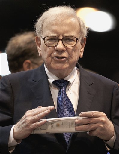 In this May 5, 2012, photo, Warren Buffett, chairman and CEO of Berkshire Hathaway, holds a newspaper at a shareholders meeting in Omaha, Neb.