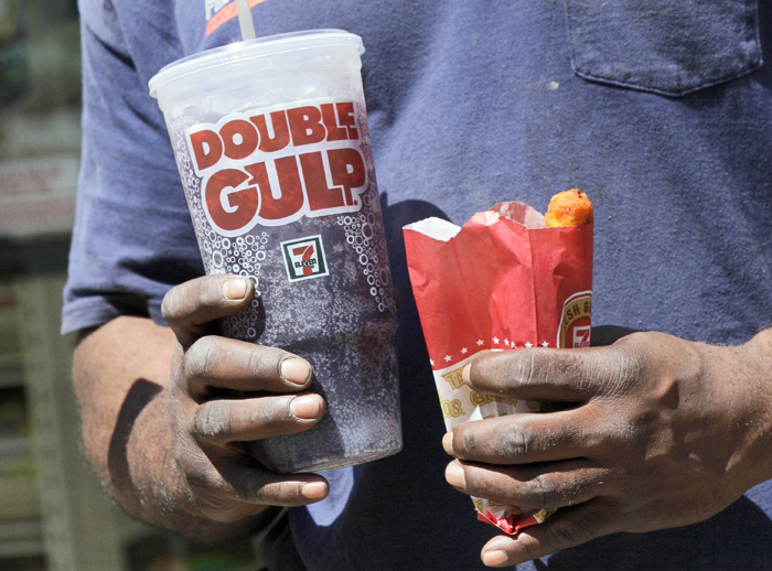 A man leaves a 7-Eleven store with a Double Gulp drink in New York today. New York Mayor Michael Bloomberg is proposing a ban on the sale of large sodas and other sugary drinks in the city's restaurants, delis and movie theaters in the hopes of combating obesity.
