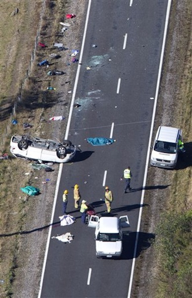 Police and fire crew examine the scene of a minivan crash near Turangi, New Zealand, Saturday, May 12, 2012. Three Boston University students who were studying in New Zealand were killed Saturday when their minivan crashed. At least five other students from the university were injured in the accident, including one who was in critical condition. (AP Photo/New Zealand Herald, John Cowpland)