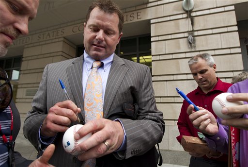 Former Major League Baseball pitcher Roger Clemens autographs baseballs as he leaves the Federal Court in Washington on Wednesday.