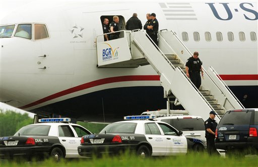 Law enforcement officials stand on a jet bridge and a passenger jet on the tarmac at Bangor International Airport, in Bangor, Me., Tuesday, May 22, 2012. The plane was diverted to Maine during its flight from France to Charlotte. Officials briefed on the incident say a French passenger passed a note to a flight attendant saying she had a surgically implanted device. (AP Photo/Bangor Daily News, Kevin Bennett)