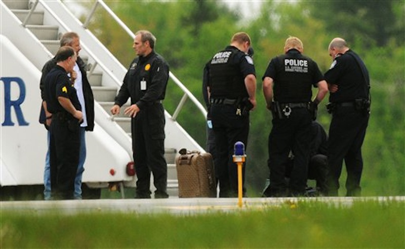 Law enforcement officials stand near a jet bridge next to a passenger jet on the tarmac at Bangor International Airport, in Bangor, Me., Tuesday, May 22, 2012. The plane was diverted to Maine during its flight from France to Charlotte. Officials briefed on the incident say a French passenger passed a note to a flight attendant saying she had a surgically implanted device. (AP Photo/Bangor Daily News, Kevin Bennett)