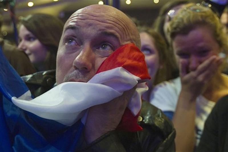 A supporter of outgoing French President Nicolas Sarkozy's Union for a Popular Movement (UMP) covers his face with the national flag as the preliminary results of the second round of the presidential elections were announced at UMP headquarters in Paris Sunday May 6, 2012. The first results showed a 52 percent lead for Socialist Party candidate Francois Hollande. (AP Photo/Michel Euler)