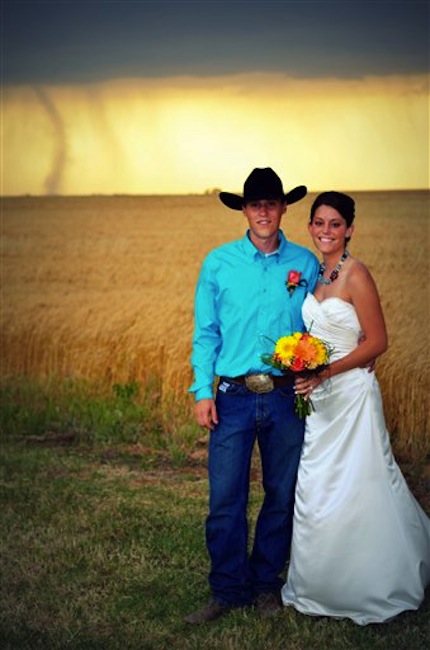 In this May 19, 2012, photo provided by Cate Eighmey, Caleb & Candra Pence pose for a wedding photo as a tornado swirls in the background after they were married in Harper County, Kan. (AP Photo/Cate Eighmey)