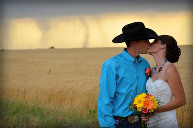 In this May 19, 2012, photo provided by Cate Eighmey, Caleb & Candra Pence pose for a wedding photo as a tornado swirls in the background after they were married in Harper County, Kan. (AP Photo/Cate Eighmey)
