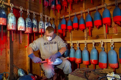 Lobsterman Kendall Delano sands last year's paint off lobster buoys he's painting in his workshop in Friendship on Thursday.