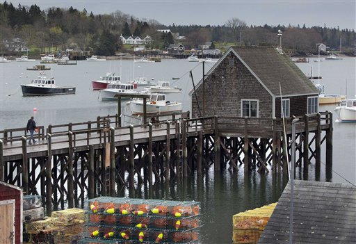 A man walks out on a wharf in Friendship's postcard-pretty harbor, where two sabotaged lobster boats were cut free and allowed to flood with water.