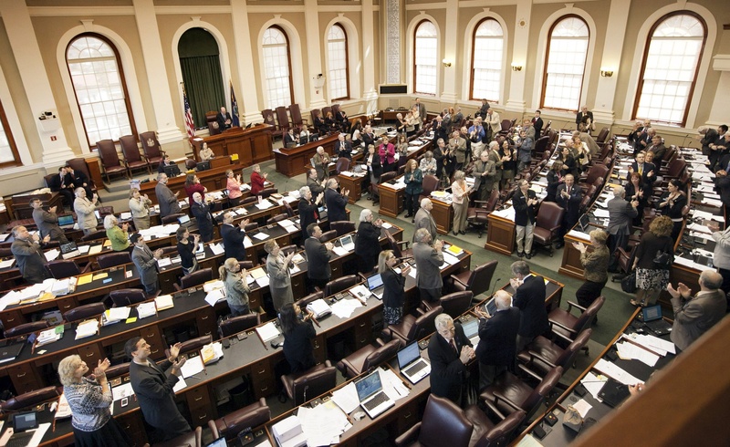 Legislators stand and applaud visitors in the House chamber during a session last month at the State House. Today, legislators are expected to debate a budget tailored by the Republicans to get the governor's support.