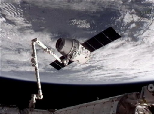 This image provided by NASA-TV shows the SpaceX Dragon commercial cargo craft, top, after Dragon was grappled by the Canadarm2 robotic arm and connected to the International Space Station, Friday, May 25, 2012. Dragon is scheduled to spend about a week docked with the station before returning to Earth on May 31 for retrieval. (AP Photo/NASA)