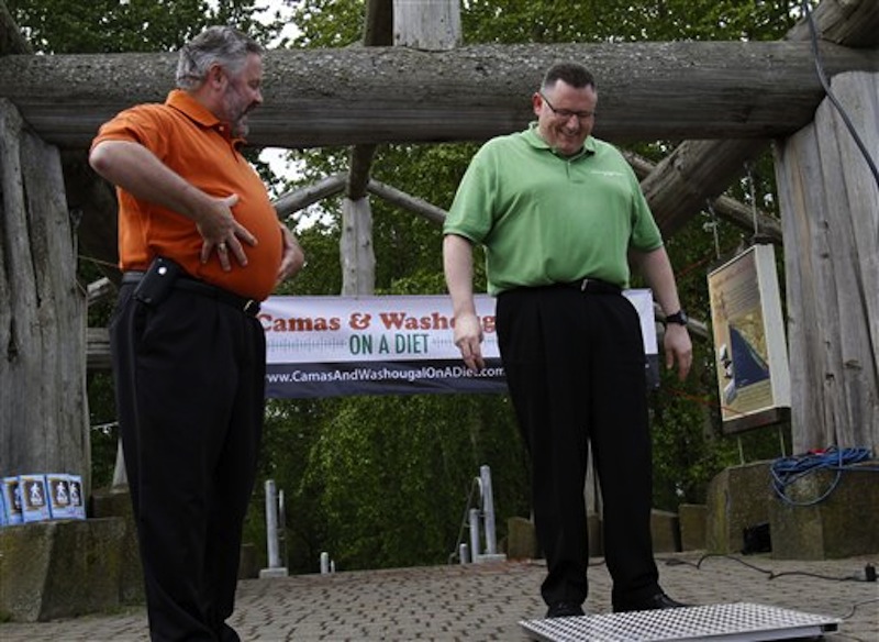 In this May 2, 2012 file photo, Washougal Mayor Sean Guard, left, coaxes Camas Mayor Scott Higgins to step on the scales during their weigh-in in Washougal, Wash. The mayors of the two neighboring towns are in a "Biggest Loser" style contest to see which of the two communities can lose the most weight. New government projections suggest roughly 42 percent of Americans will be obese by 2030. (AP Photo/Don Ryan)