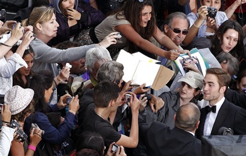 Actor Robert Pattinson, foreground right, greets fans as he arrives for the screening of Cosmopolis at the 65th international film festival, in Cannes, southern France, Friday, May 25, 2012. (AP Photo/Vincent Kessler, Pool)