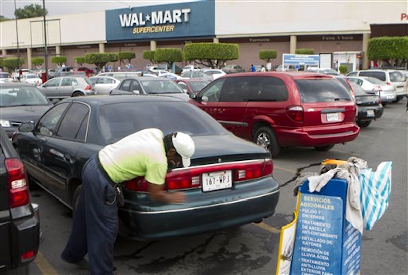 In this Saturday, April 21, 2012 photo, a man cleans a car in the parking outside a Walt-Mart Super Center. Wal-Mart will install solar panels at all its Massachusetts stores within the next two years. (AP Photo)
