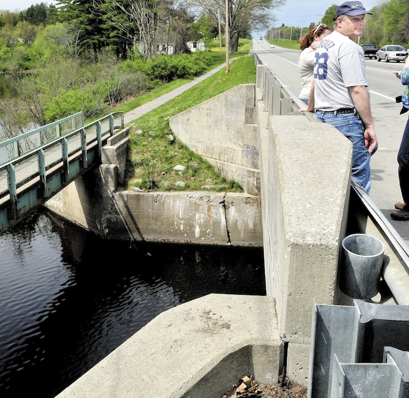 Ken Gagnon of Waterville and his daughter Bethany stand on a bridge on U.S. Route 201 in Hinckley over Martin Stream on Sunday. Police divers searched under water for his sister Cora Marley of Skowhegan, who police say went off the roadway in her vehicle Saturday evening and into the water.