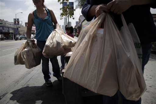 Two women wait for a bus after their grocery shopping in Los Angeles, Thursday, May 24, 2012. Now that the city of Los Angeles has taken the first step toward banning plastic bags, it appears the little utilitarian bags themselves may be headed for the trash heap of history. (AP Photo/Jae C. Hong)