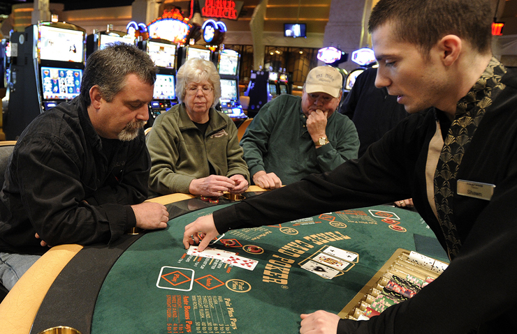 Shawn Hollobaugh, right, deals cards to Tom Gagne of Bangor, left, as others watch during a game of three card poker at the Hollywood Casino in Bangor in this March 16 photo. When compared with 2010 figures, Maine’s gross gaming revenue dropped by 3.6 percent in 2011. and its gaming tax receipts fell by 3.7 percent year-over-year.