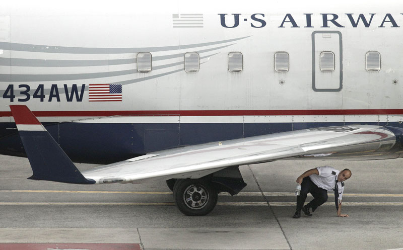 A member of the flight crew on U.S., Airways commuter jet, tail number N434AW, completes a walk-around of the aircraft at Logan International Airport in Boston, yesterday. A man has been arrested in Boston after allegedly trying to open a cabin door of the jet flying from Maine to Philadelphia.